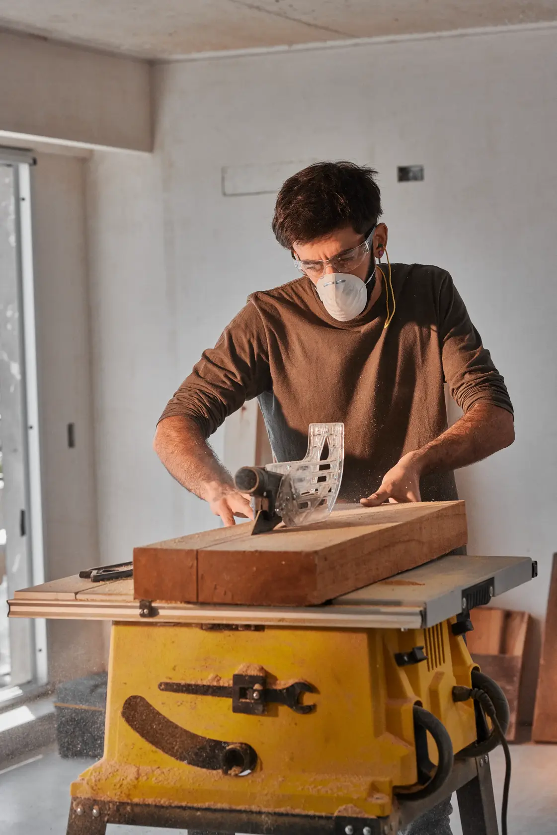 Photo of a person using a STANLEY SST2001-B2 table saw to cut wood indoors, yellow base visible.