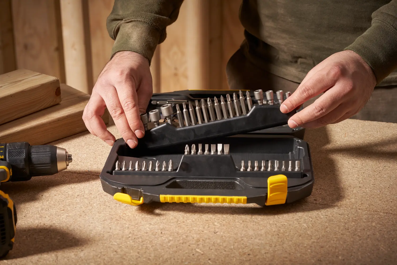 STANLEY STA7184 drill bit set in black and yellow case, open on workbench with person handling.