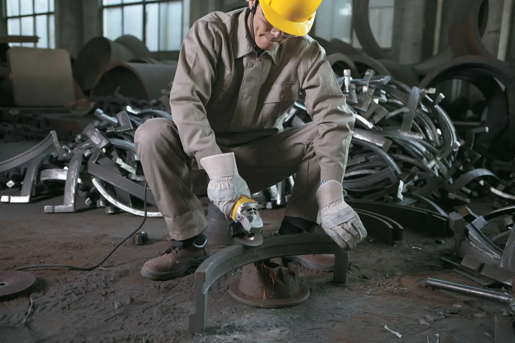 STANLEY STGS9125 angle grinder used by worker in protective gear grinding metal part in industrial setting.
