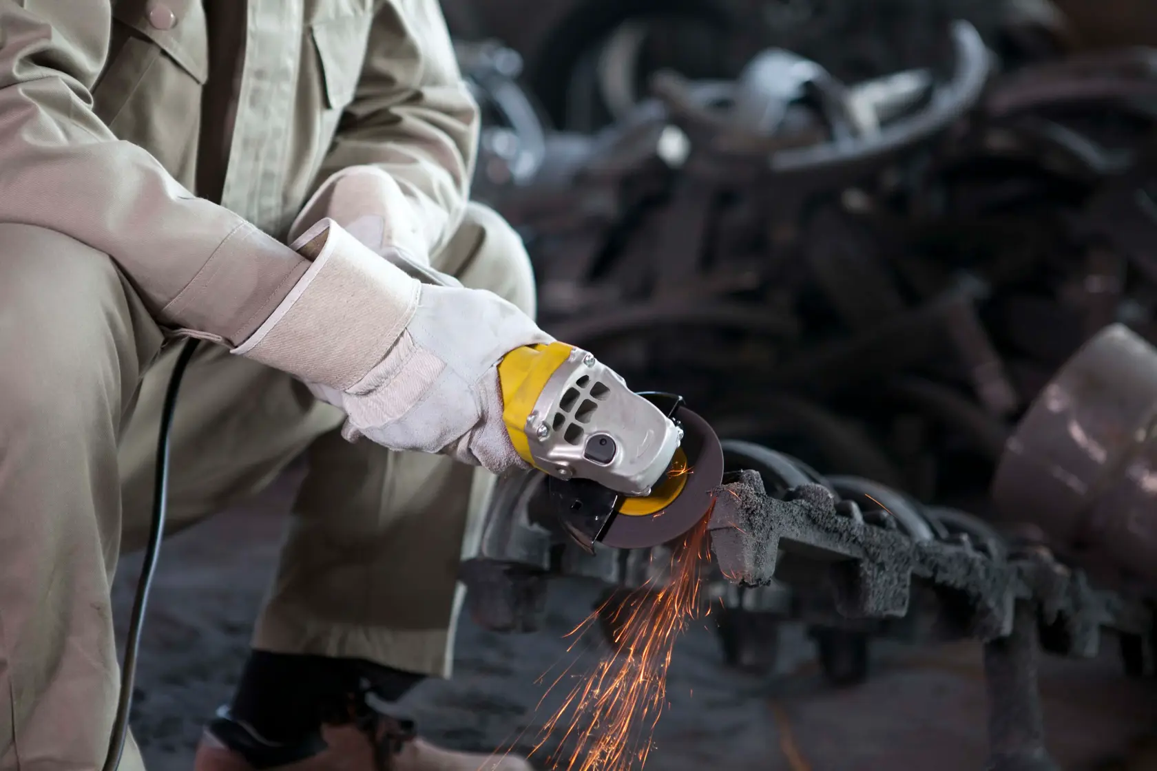 STANLEY STGT8100 angle grinder in use, grinding metal part, close-up, sparks visible, industrial setting.