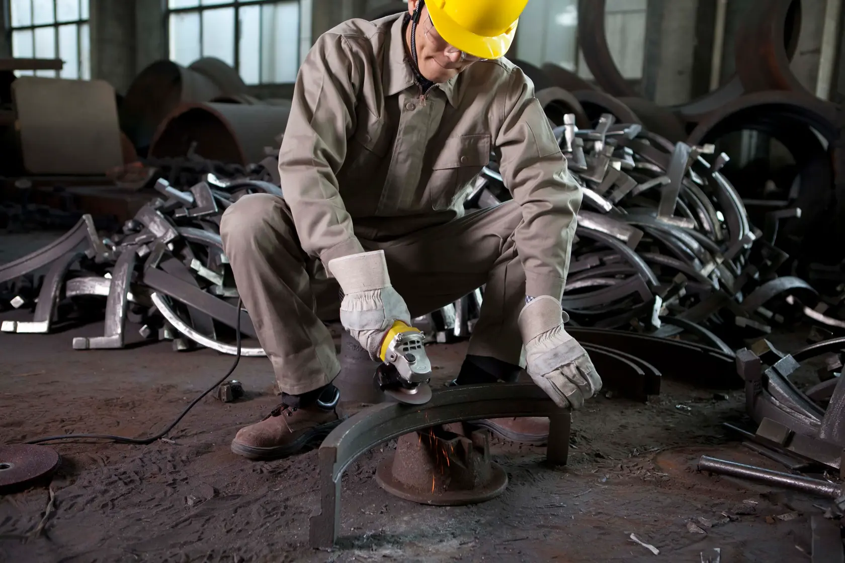 STANLEY STGT8100 angle grinder in use by worker in protective gear, grinding metal in an industrial setting.