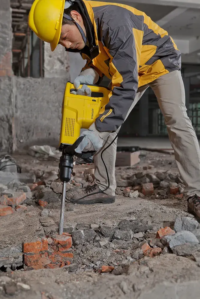 Stanley STHM10K demolition hammer shown in use breaking concrete rubble at a construction site.