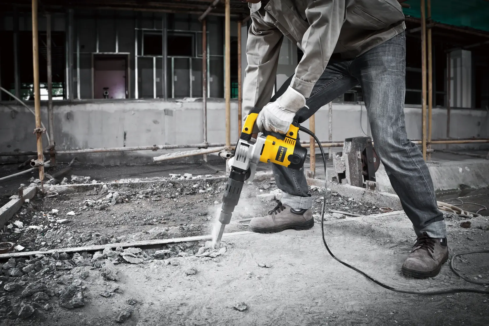 STANLEY STHM5KH demolition hammer in use breaking concrete at construction site, frontal angle.