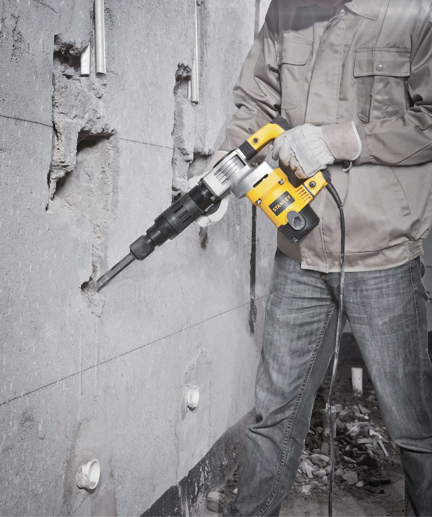 Stanley STHM5KH demolition hammer breaking concrete wall, handheld power tool in use.
