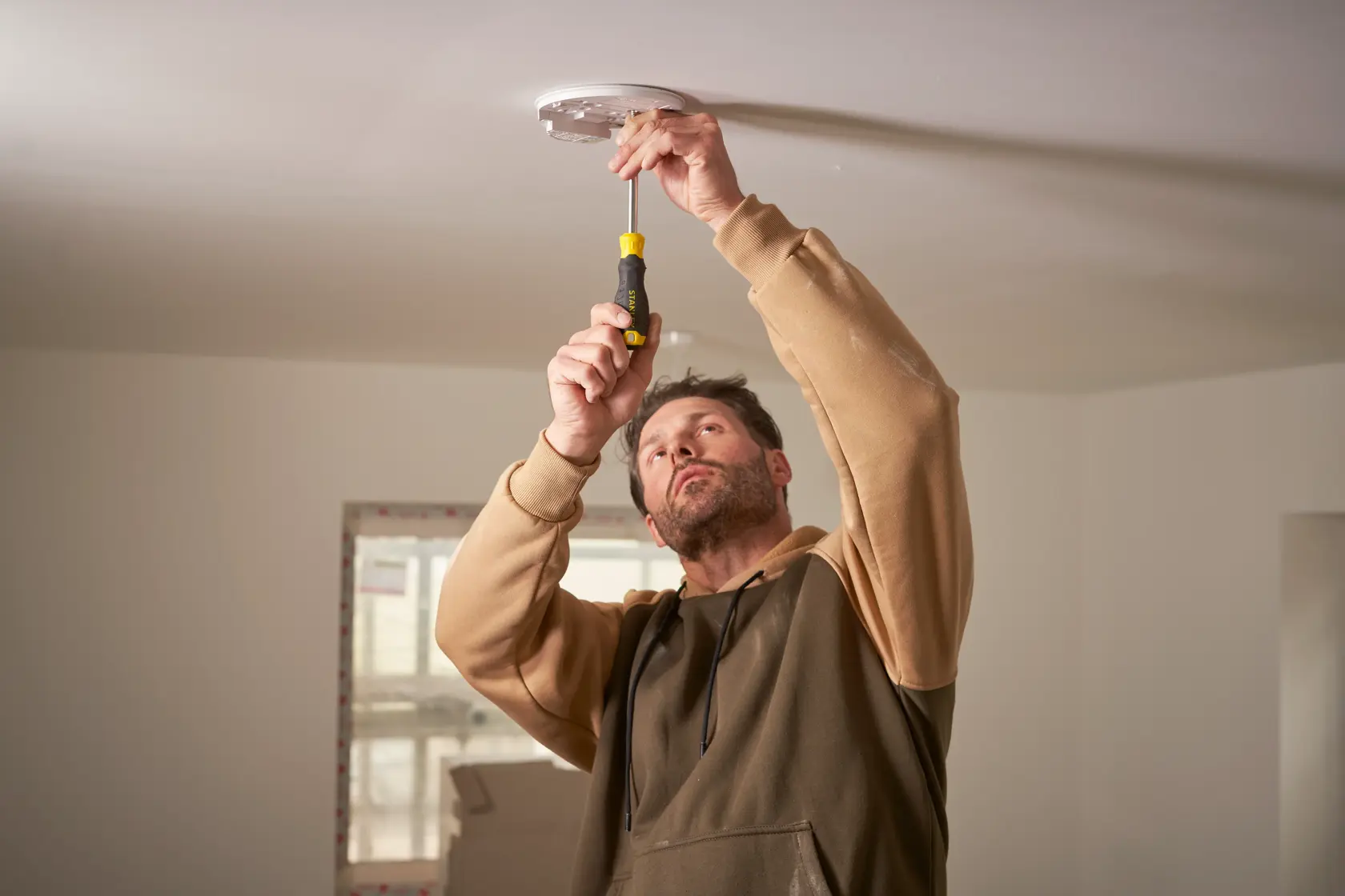 Photo of STANLEY STHT0-70885 hand screwdriver used for ceiling fixture installation, indoor setting.