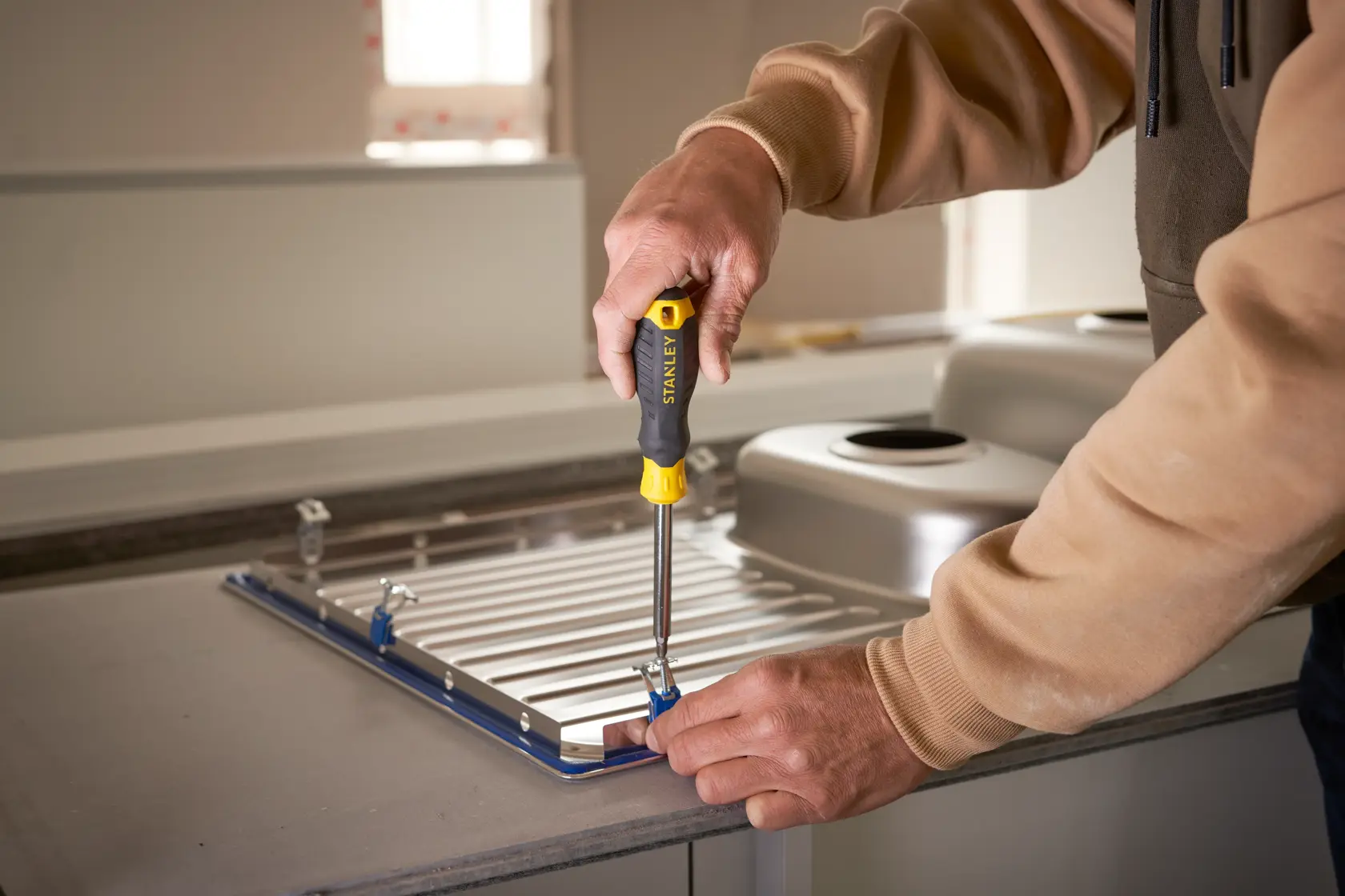 Photo of STANLEY STHT0-70885 screwdriver used to fasten metal brackets on a kitchen sink panel.