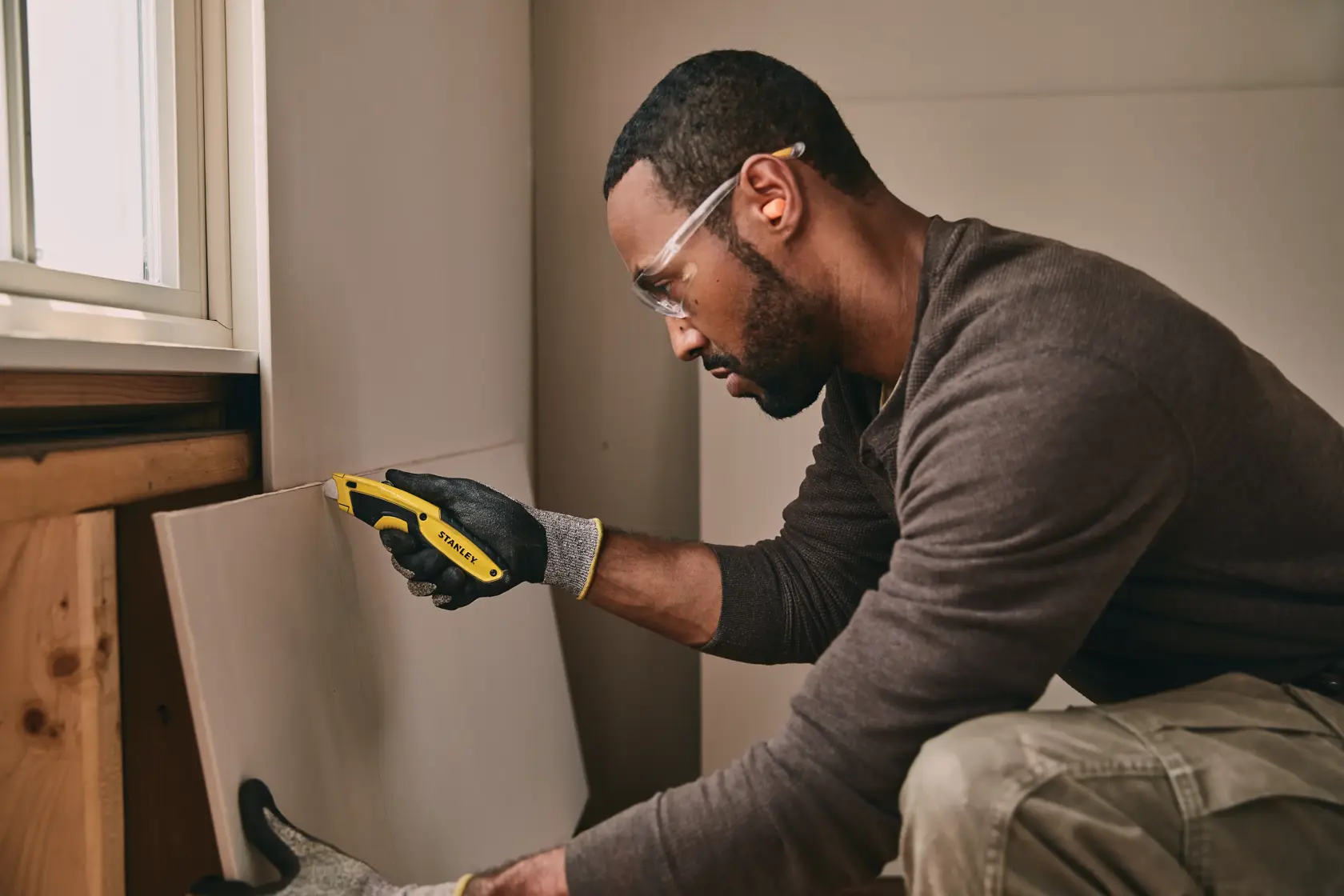 STANLEY STHT10479-0 utility knife used for drywall cutting, shown in a construction setting.