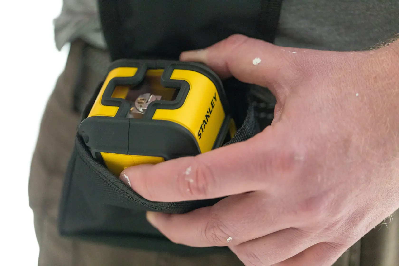 STANLEY STHT77498-1 yellow laser level being held and placed in a black pouch, close-up photography.