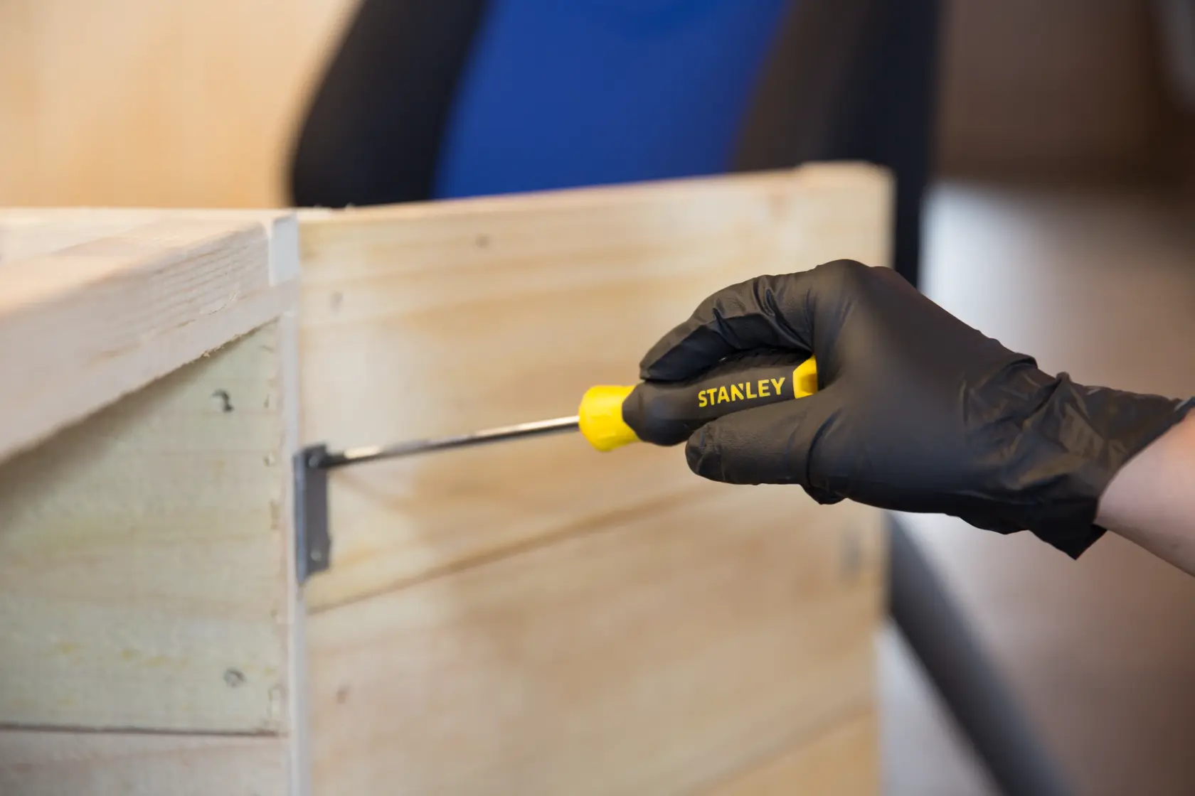 Photo of STANLEY STMT60811-8 screwdriver used on wood, yellow handle held by black-gloved hand.