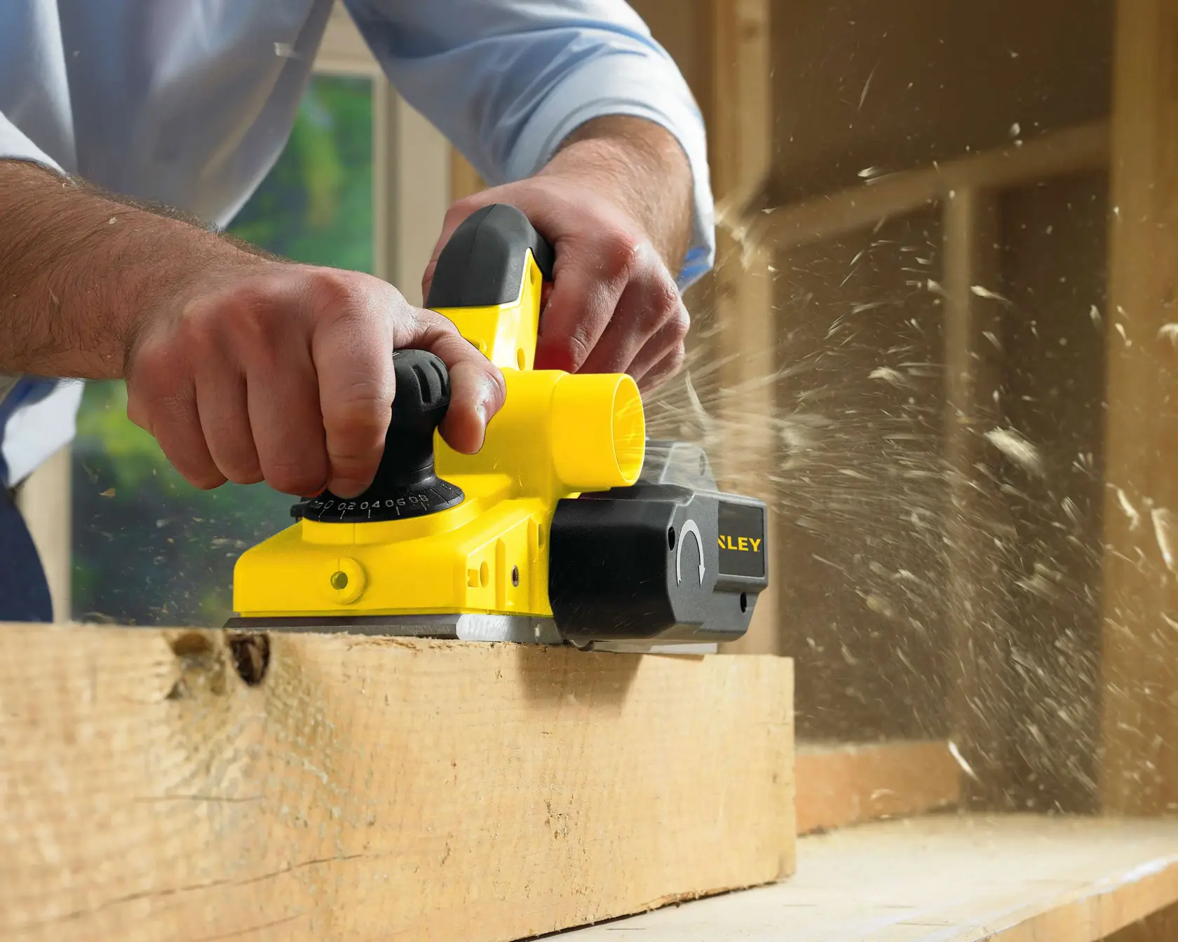 Stanley STPP7502-B2 electric planer being used on wood, close-up photography, yellow and black tool.