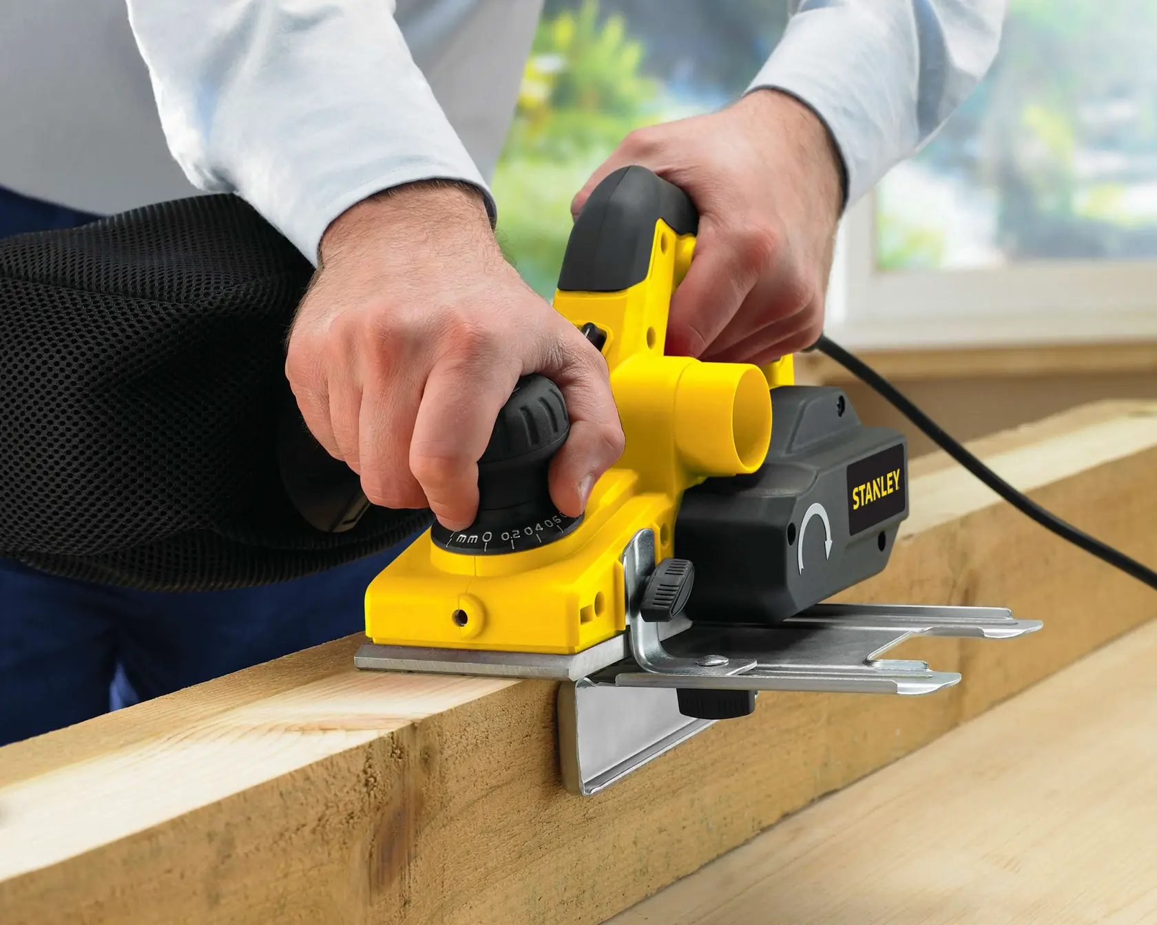 STANLEY STPP7502-B2 electric planer with black handle in use on wood, close-up angle.