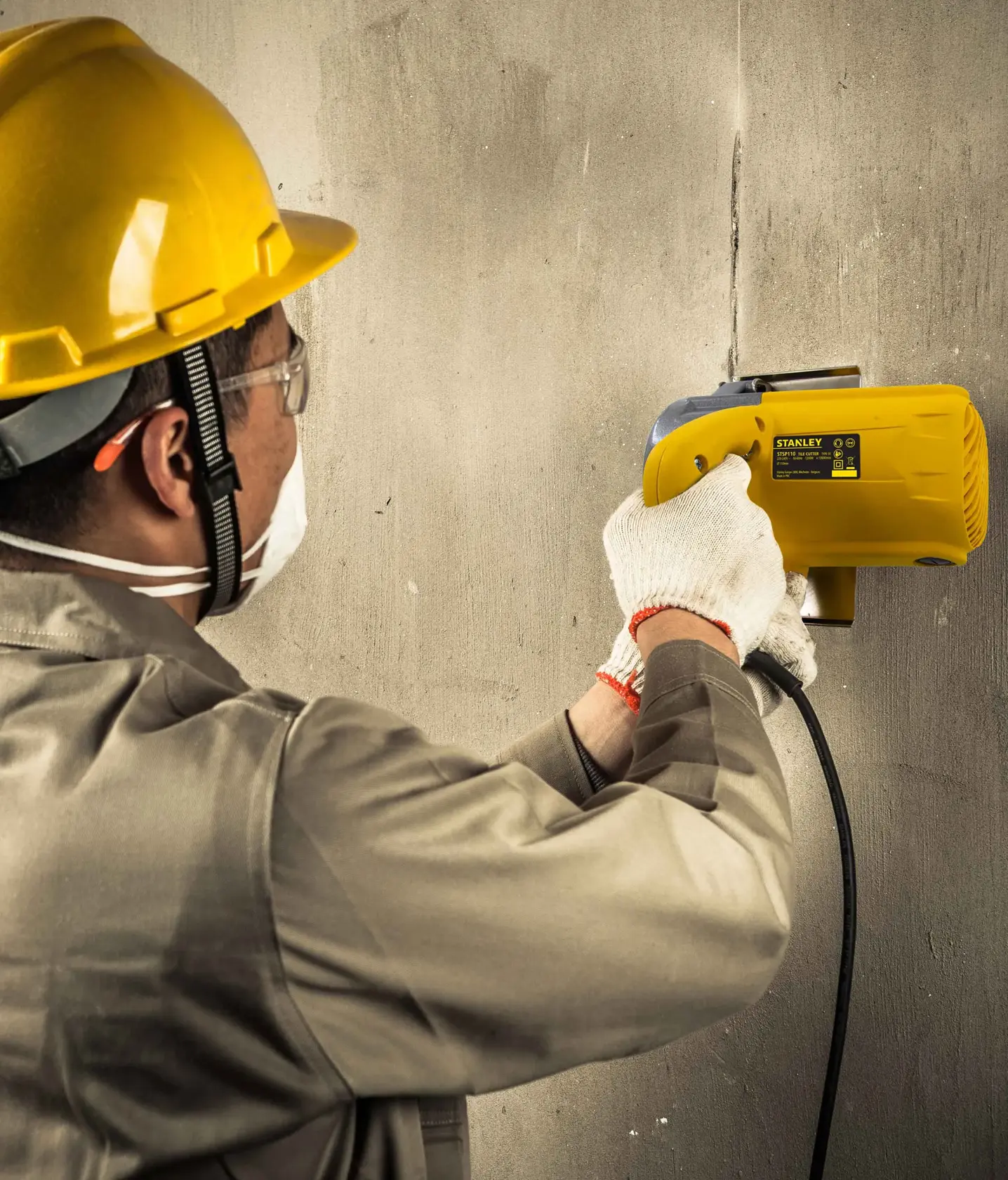 Stanley STSP110 electric wall cutter in use, side view, operated by worker in safety gear.