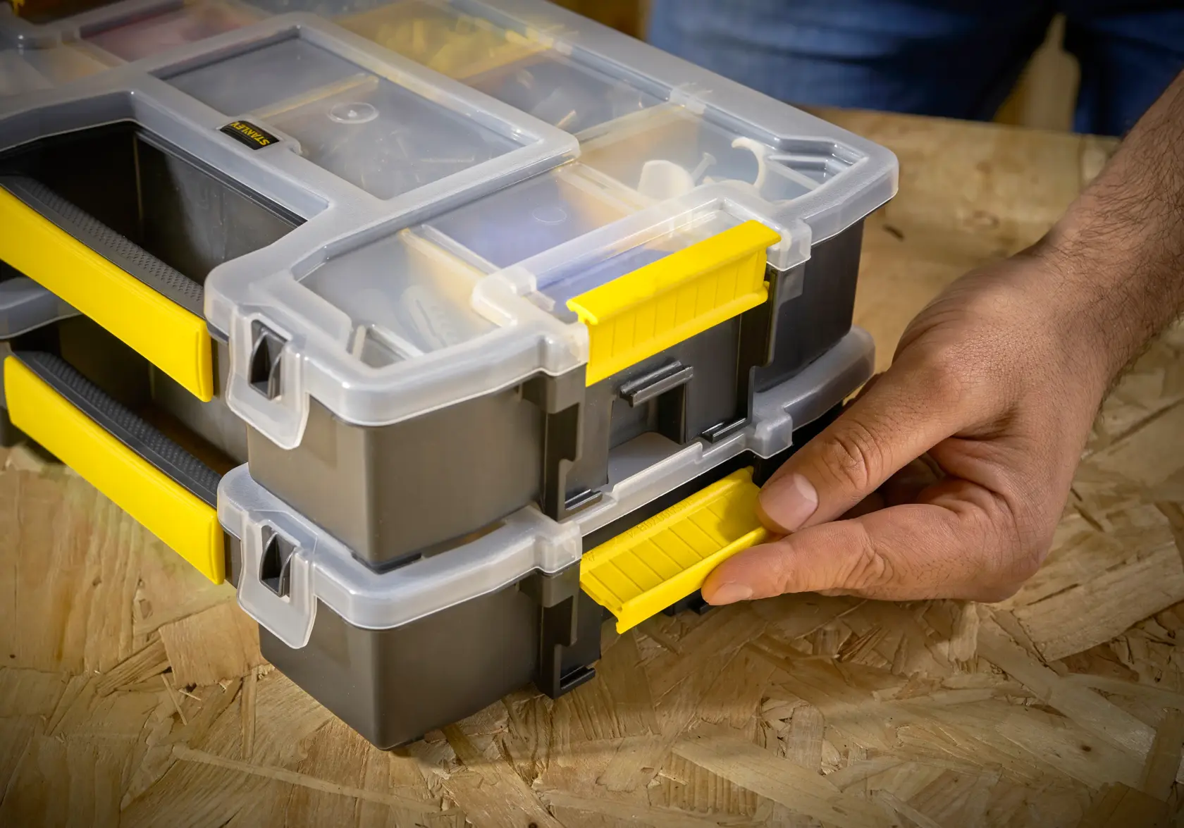 STANLEY STST1-70720 organizer box with yellow latch, stacked, close-up of hand opening latch.