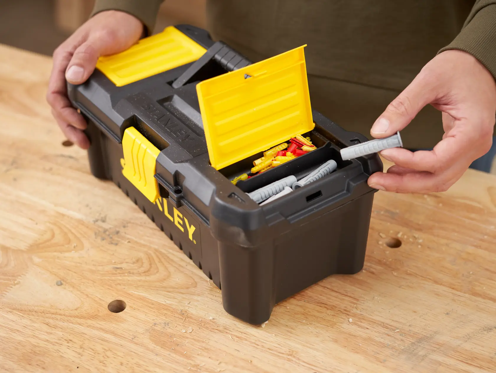 Stanley STST1-75514 toolbox with yellow lid open, showing compartments with fixings on workbench.