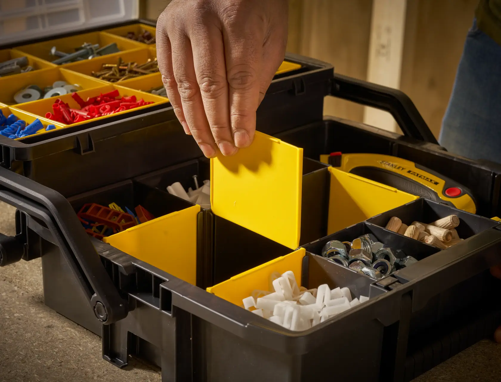 STANLEY STST1-75540 organizer box with yellow compartments, hand adjusting divider, close-up angle.