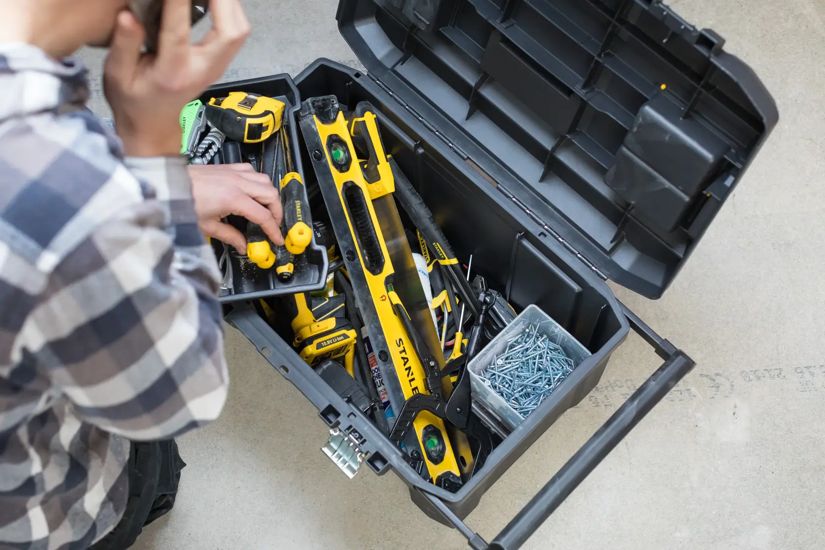 STANLEY STST1-80150 toolbox with yellow hand tools and nails, top view, open on concrete floor.