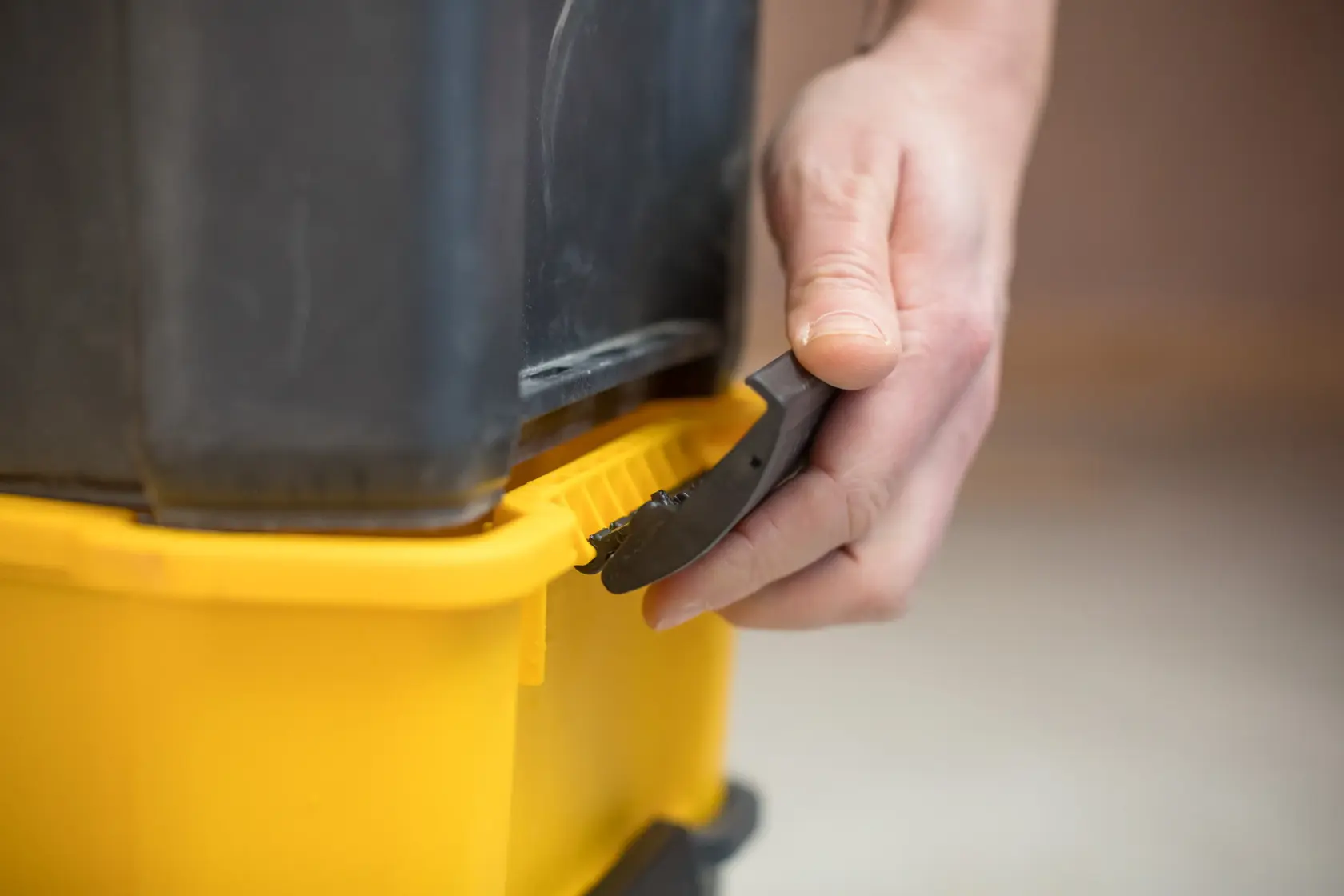 STANLEY STST1-80151 photography of tool used to open yellow storage box lid close-up.