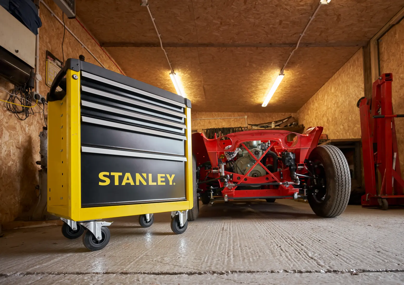 Photo of STANLEY STST74305-1 yellow and black rolling tool cabinet in a garage, shown front left angle.
