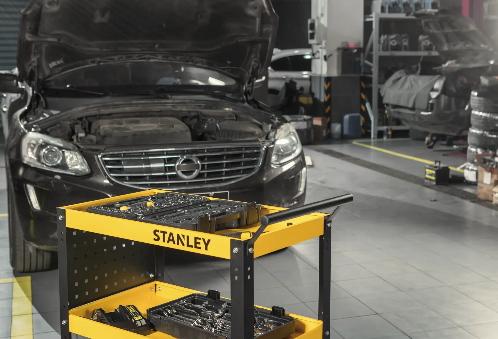 STANLEY STST74321-8 yellow tool cart with trays in auto repair workshop, front angle.