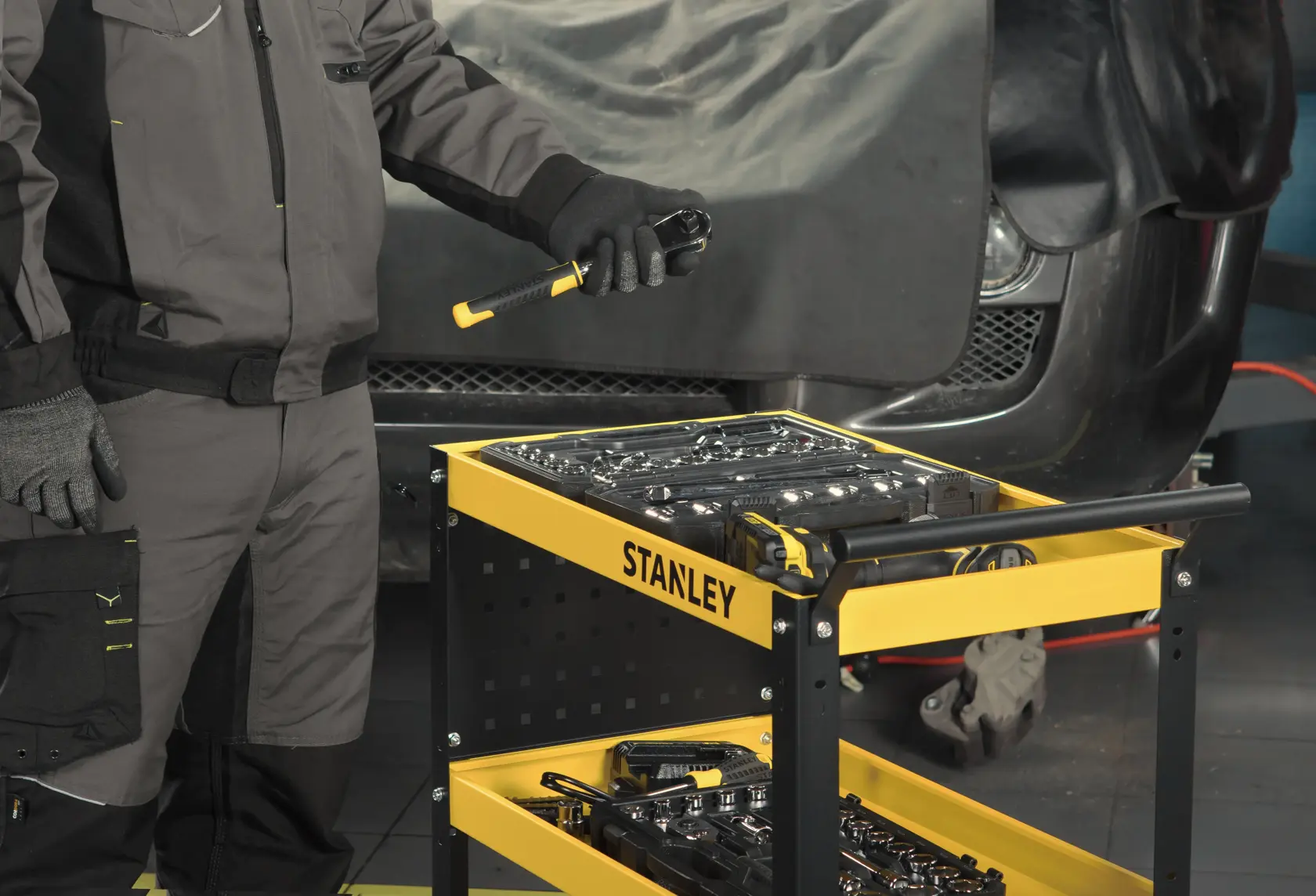 Stanley STST74321-8 yellow tool trolley with tools, side view in workshop setting.