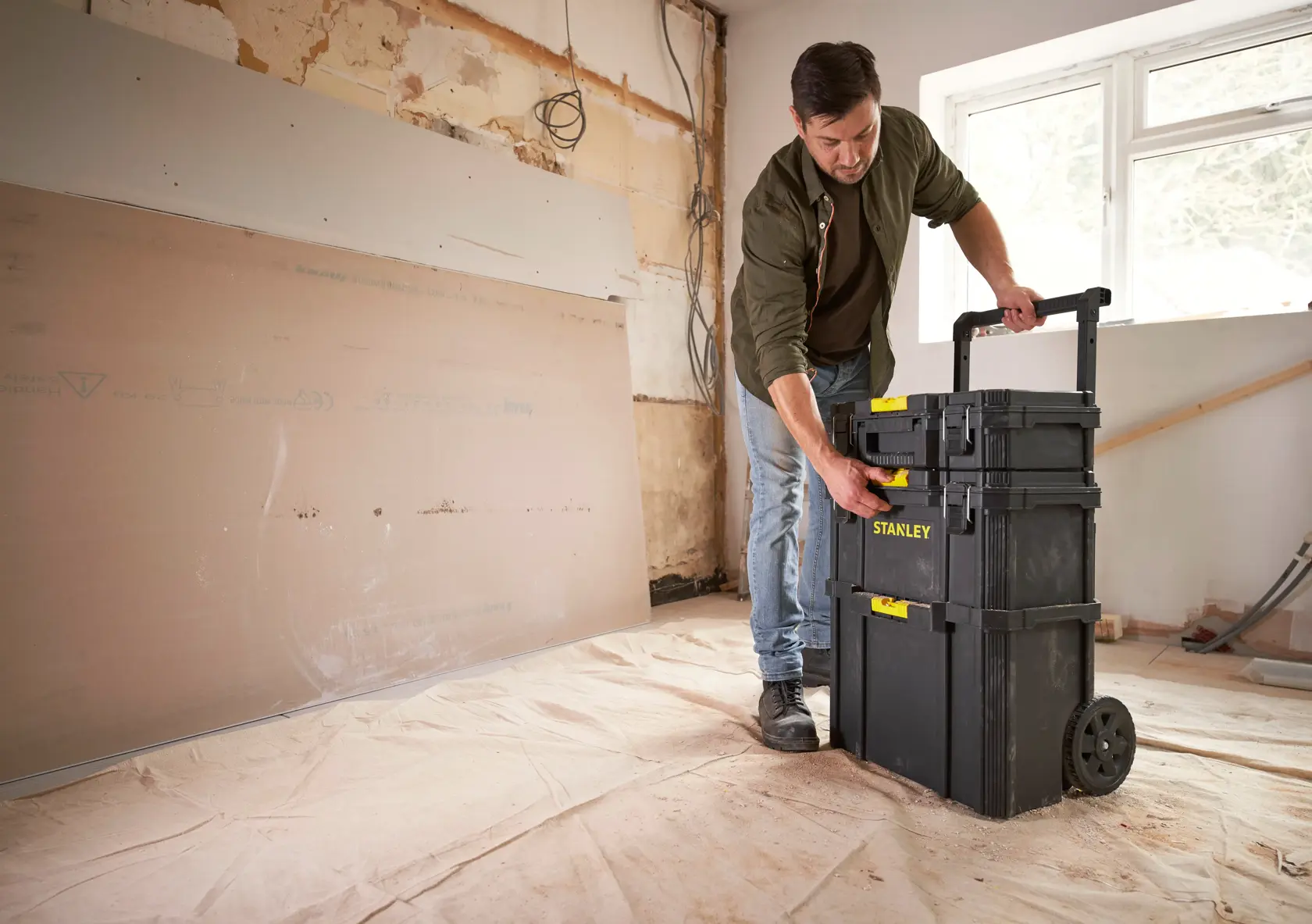 STANLEY STST83319-1 rolling black tool chest stack with yellow latches in a renovation room, person accessing top box.